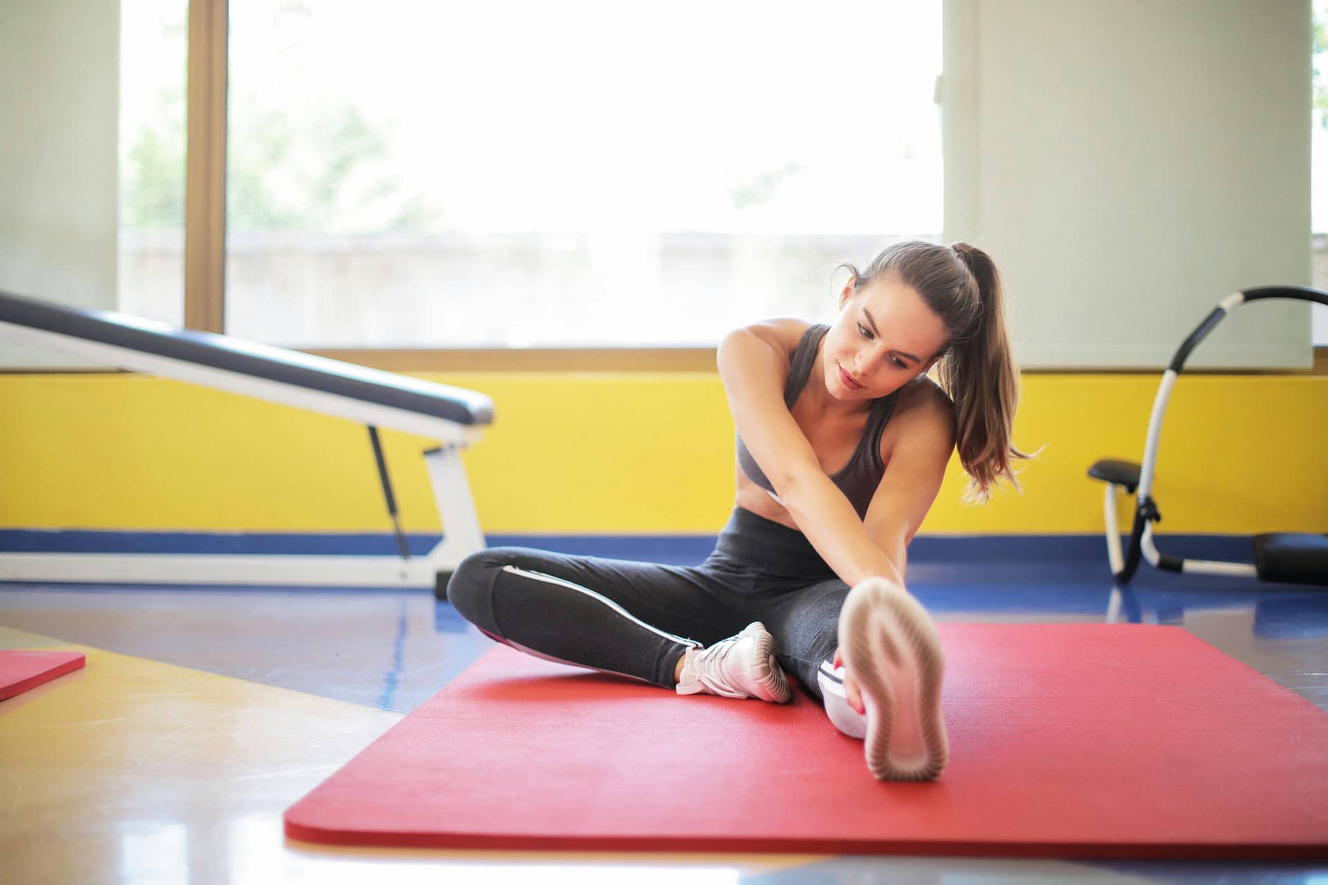 Frau Im Schwarzen Sport Bh Und Im Schwarzen Legging, Die Auf Roter Yogamatte Sitzen